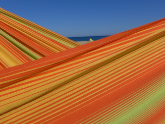 Détail du tissu rayé orange, jaune et vert sous un ciel bleu