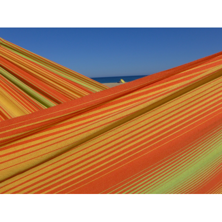 Détail du tissu rayé orange, jaune et vert sous un ciel bleu