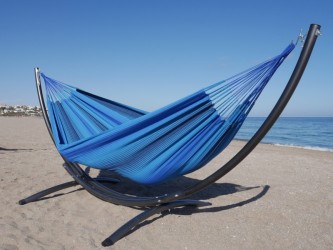 Un hamac colombien aux tons bleus installé sur un support en métal noir situé dans la mer