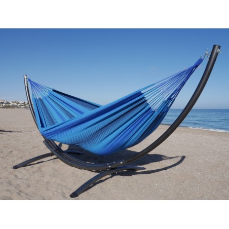Un hamac colombien aux tons bleus installé sur un support en métal noir situé dans la mer