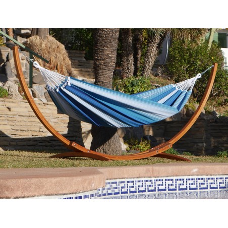 Hamac XXL rayé bleu et blanc avec support en bois suspendu dans un jardin avec des palmiers