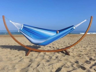 Hamac rayé bleu et blanc avec support en bois sur une plage de sable doré