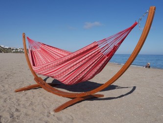 Un hamac poligono rouge et blanc suspendu à un support en bois dans la mer