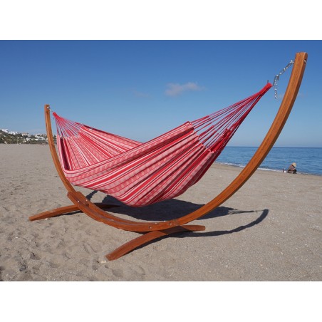 Un hamac poligono rouge et blanc suspendu à un support en bois dans la mer