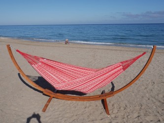 Un hamac poligono rouge et blanc suspendu à un support en bois dans la mer