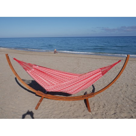 Un hamac poligono rouge et blanc suspendu à un support en bois dans la mer