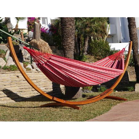 Un hamac poligono rouge et blanc suspendu à un support en bois dans un décor de jardin