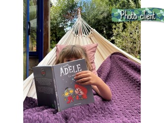 Photo d'une cliente, une petite fille lisant un livre animé, bien au chaud et profitant de son hamac avec support en bois