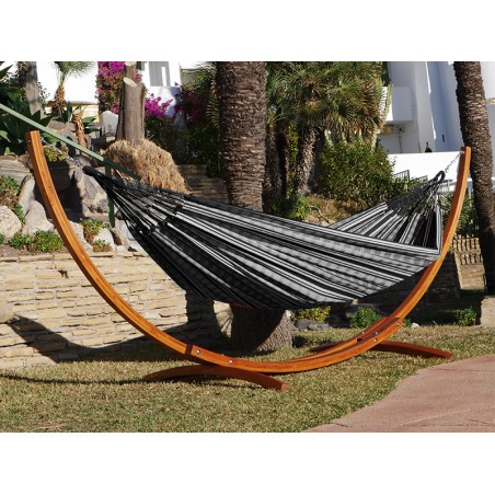 Hamac polygone noir XL avec support en bois, situé dans un jardin ensoleillé
