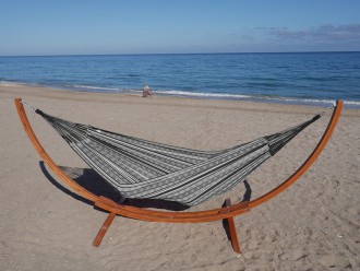 Hamac polygone noir XL allongé avec support en bois, au bord de la mer