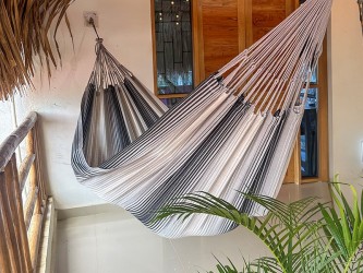 Hamac artisanal colombien gris et blanc suspendu sur une terrasse