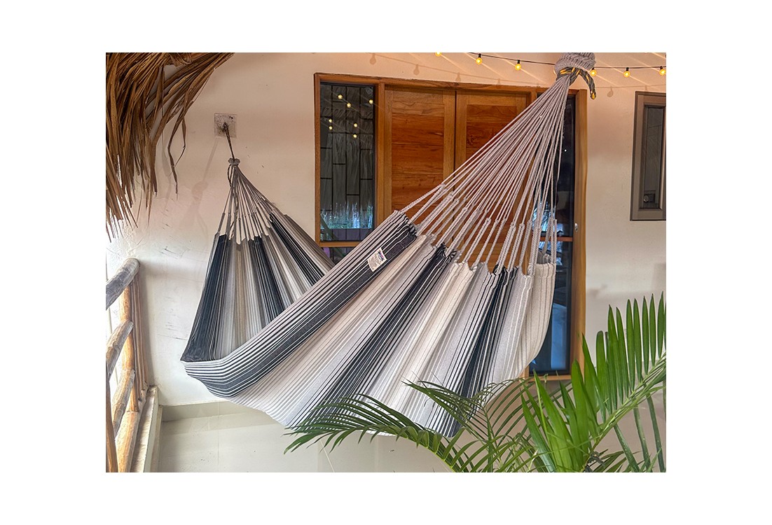 Hamac artisanal colombien gris et blanc suspendu sur une terrasse