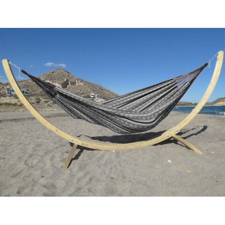 Hamac colombien à rayures noires et blanches sur un support en bois incurvé, au bord de la mer