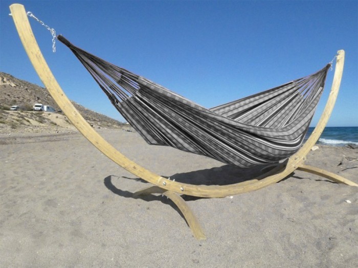 Hamac colombien à rayures noires et blanches sur un support en bois incurvé, au bord de la mer