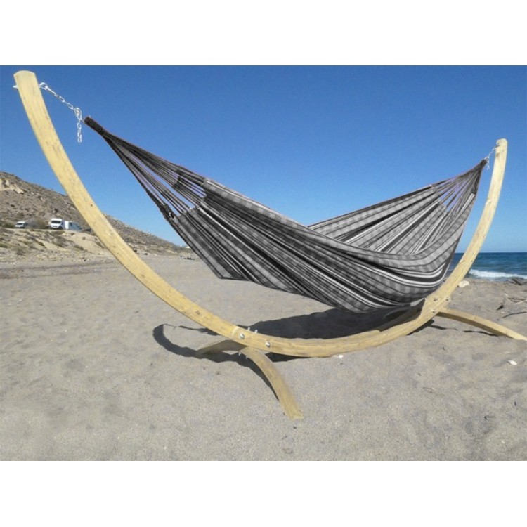 Hamac colombien à rayures noires et blanches sur un support en bois incurvé, au bord de la mer