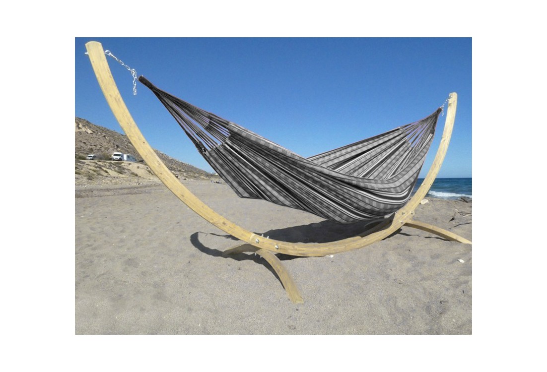 Hamac colombien à rayures noires et blanches sur un support en bois incurvé, au bord de la mer