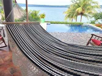 Hamac artisanal à barre, noir et écru suspendu dans un jardin tropical, parfait pour se relaxer au bord de la piscine