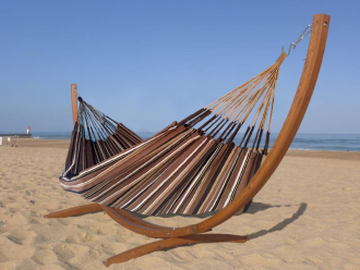 Hamac dans les tons marron en coton recyclé avec support en bois situé en mer