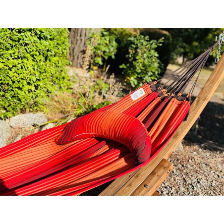 Coussin sur un hamac en tissu à rayures rouges est suspendu dans un jardin