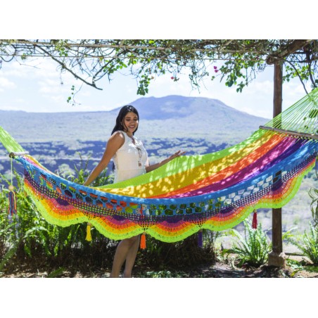 Femme posant et se relaxant dans un hamac aux couleurs vives dans un environnement naturel ensoleillé