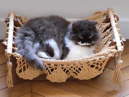 Hamac pour chat couleur taupe et support en bois avec un chat gris et blanc qui dort