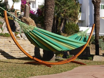 Hamac XL vert à rayures jaunes avec support de hamac en bois dans un jardin
