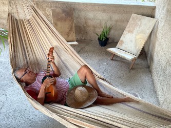 Homme allongé dans un hamac Moriche à rayures marron sur une terrasse rustique