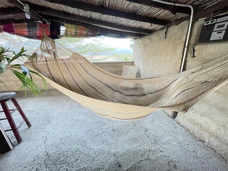 Hamac Moriche à rayures marron vu de profil sur une terrasse rustique