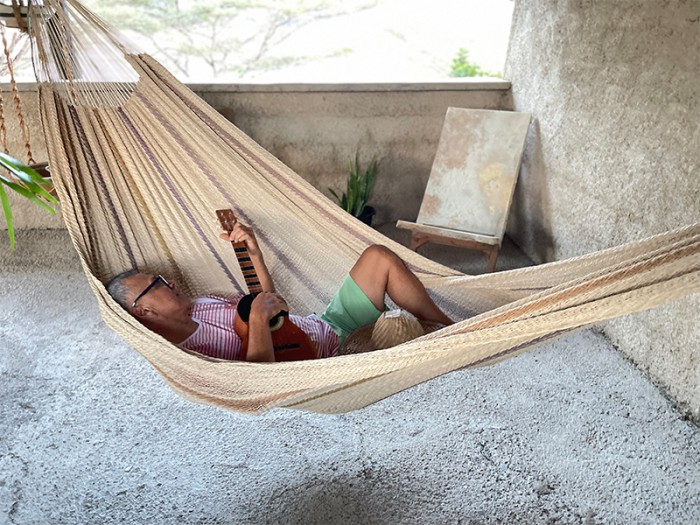 Homme allongé dans un hamac Moriche à rayures marron sur une terrasse rustique