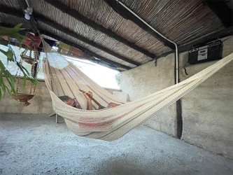 Hamac Moriche à rayures marron vu de profil sur une terrasse rustique