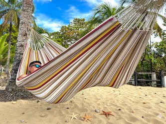 Homme se reposant dans un hamac L en Colombie, aux rayures jaunes, bordeaux et sable. Un modèle sobre et naturel