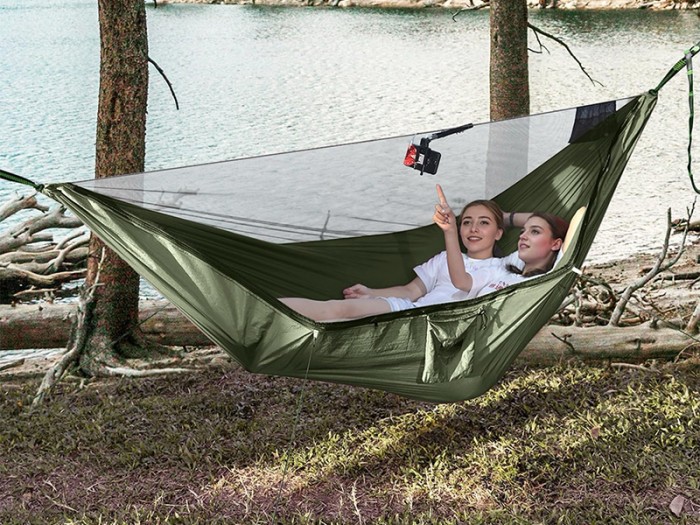 Hamac vert armée avec moustiquaire intégrée installé entre les arbres au bord du lac