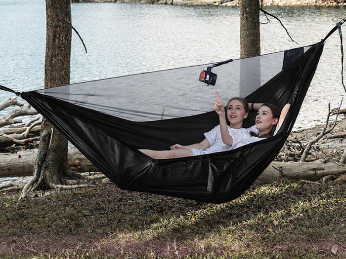 Hamac noir avec moustiquaire intégrée installé entre les arbres au bord du lac