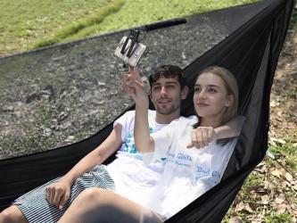 Jeunes adultes se relaxant dans un hamac parachute vert armée en pleine nature