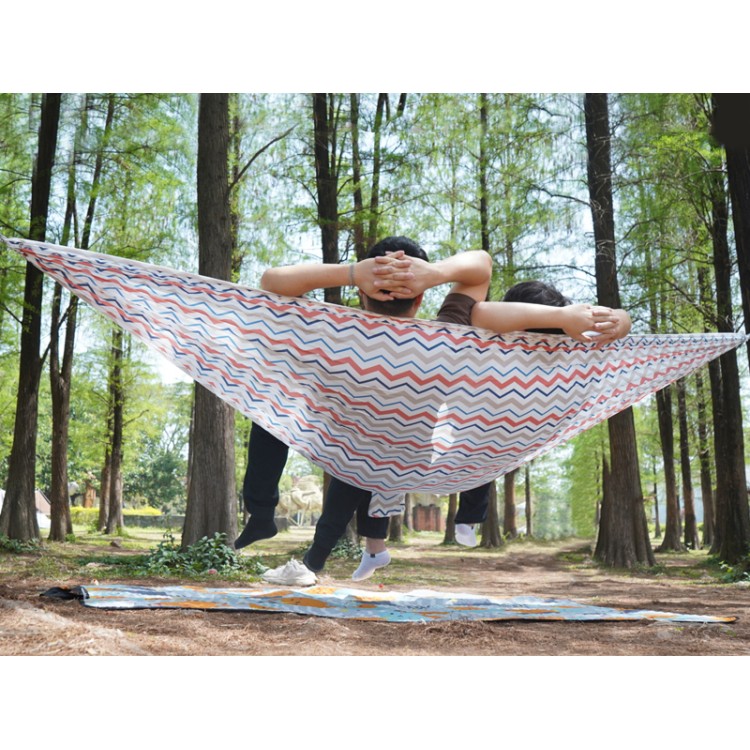 Deux personnes détendues dans un hamac explorer L nylon blanc suspendu entre deux arbres, avec une couverture au sol