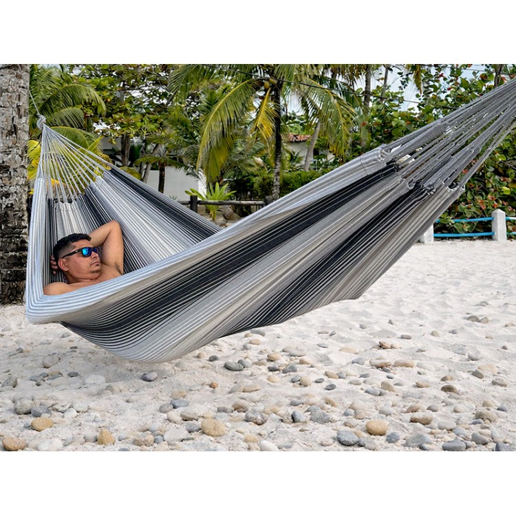 Hamac artisanal colombien en coton recyclé, tons gris et noir, suspendu entre deux arbres – confort et authenticité