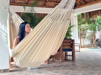 Fille assise dans un hamac CARIBE XXL Écru sur une terrasse
