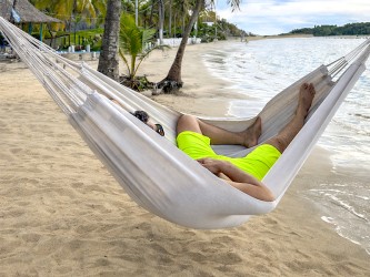 Homme se reposant dans un hamac coton recyclé L ecru au bord de la plage