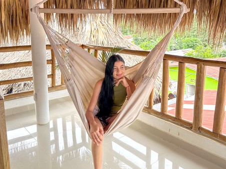 Fille assise dans un hamac chaise hamac XXL CARIBENA Ecru sur une terrasse