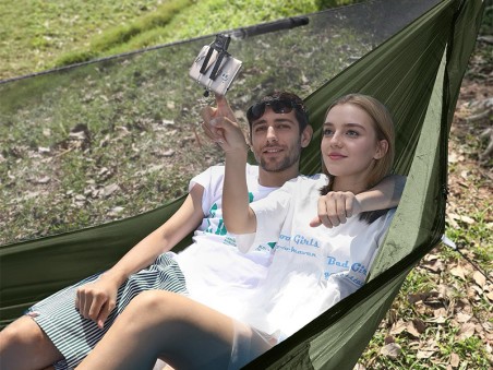 Jeunes adultes se relaxant dans un hamac parachute vert armée en pleine nature