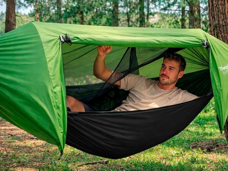 Garçon utilisant un hamac de survie avec moustiquaire et bâche anti-pluie intégrée dans la nature pour se reposer