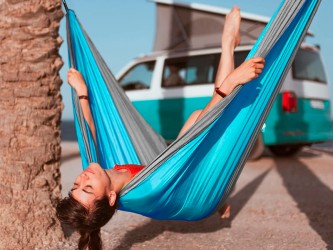 Une jeune fille sur la plage, confortablement installée dans un hamac outdoor flex XL en toile de parachute