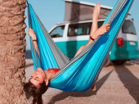 Une jeune fille sur la plage, confortablement installée dans un hamac outdoor flex XL en toile de parachute