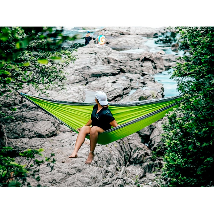 Femme assise dans un hamac outdoor flex XL Vert et gris suspendu au milieu d'une cascade en pleine nature