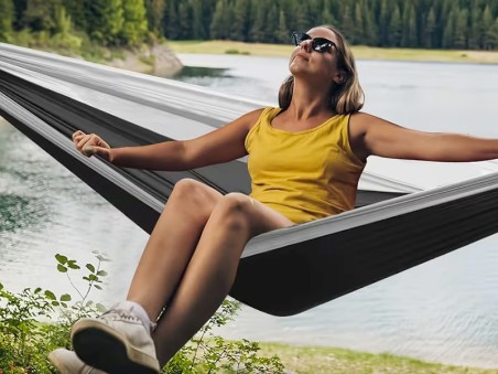 Une jeune fille suspendue dans un hamac au milieu d'un lac, en pleine forêt