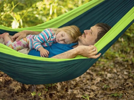 Un adulte et un enfant allongés dans le hamac, illustrant sa capacité et son confort pour un usage à deux