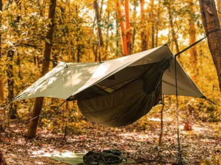 Tarp para hamaca instalado en bosque otoñal creando refugio impermeable