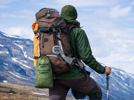 Randonneur équipé d’un tarp hamac compact fixé au sac à dos en montagne