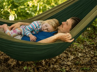 Un adulte et un enfant allongés dans le hamac, illustrant sa capacité et son confort pour un usage à deux