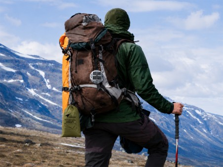 Randonneur équipé d’un tarp hamac compact fixé au sac à dos en montagne